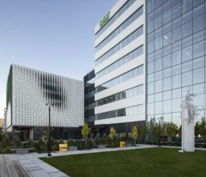 EPSYLON - Vue sur un bâtiment moderne avec une façade en verre et des espaces verts en avant-plan sous un ciel bleu clair architecturale et environnement urbain.