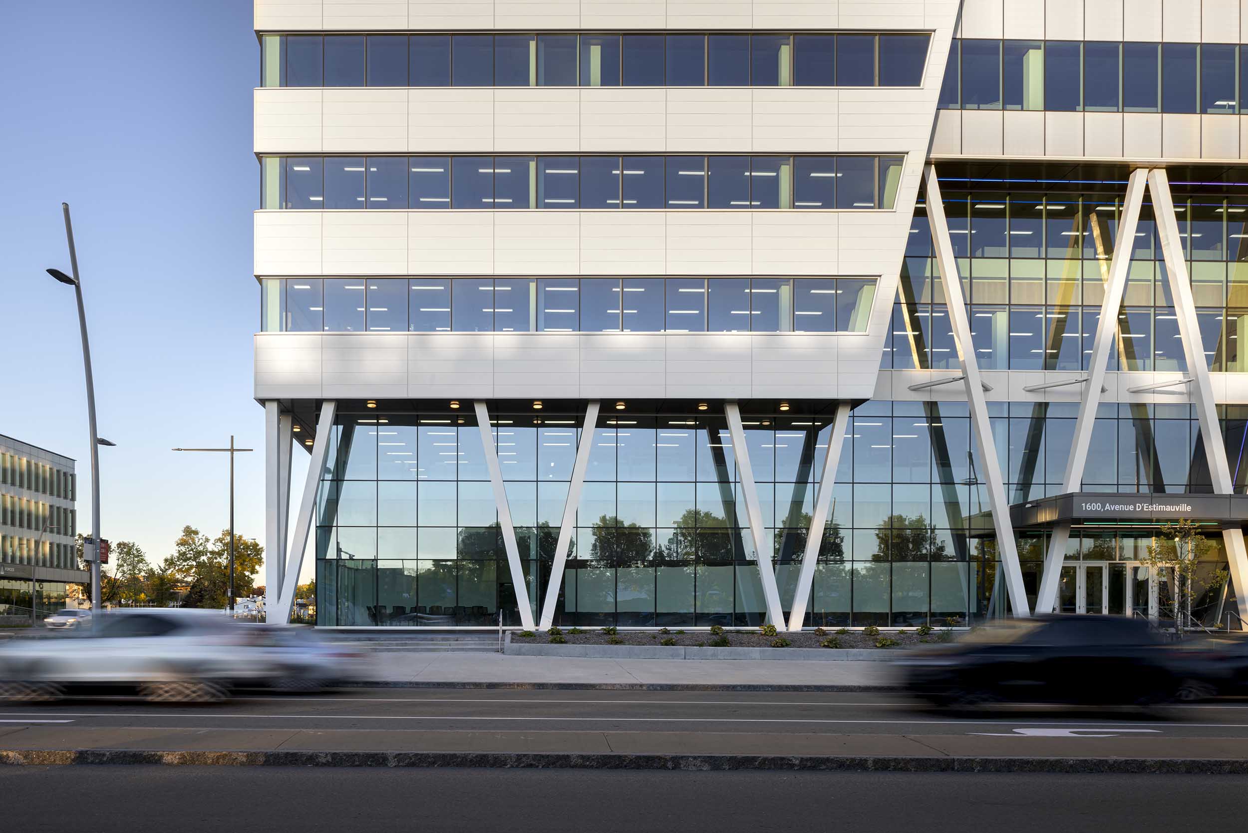 EPSYLON - Façade moderne d'un immeuble avec des voitures en mouvement au premier plan mettant en avant l'architecture contemporaine et le design urbain.