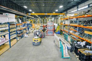 EPSYLON - Entrepôt industriel avec chariots élévateurs et rayonnages remplis de matériaux variés utilisés pour la distribution de produits et la gestion des stocks.