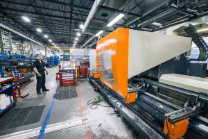 EPSYLON - Usine industrielle moderne avec machines sophistiquées. Un employé surveille le processus de fabrication dans un environnement de production haute technologie.