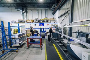 EPSYLON - L'intérieur moderne d'une usine avec des travailleurs opérant des machines industrielles de haute technologie et gestion des matériaux pour la production.