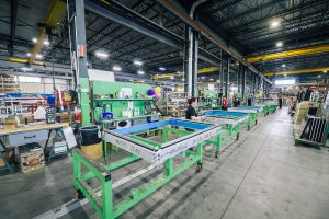 EPSYLON - Atelier industriel moderne avec travailleurs opérant des machines dans une usine bien éclairée illustrant l'efficacité et la production industrielle avancée.