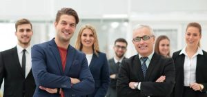 EPSYLON - Groupe de professionnels d'affaires souriant dans un bureau moderne. Equipe diverse vêtue de tenues professionnelles avec une ambiance collaborative et confiante.